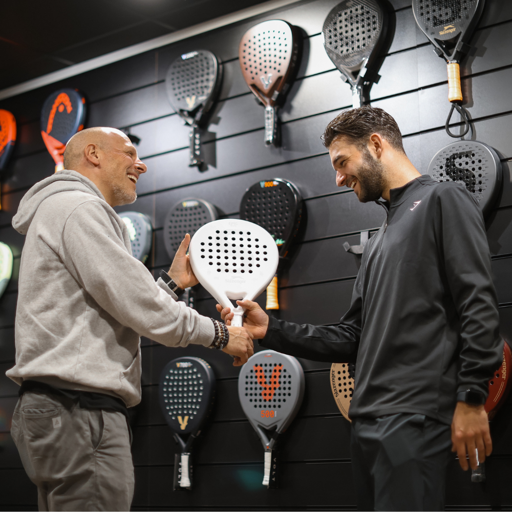 Jugador analizando palas de pádel en una tienda especializada